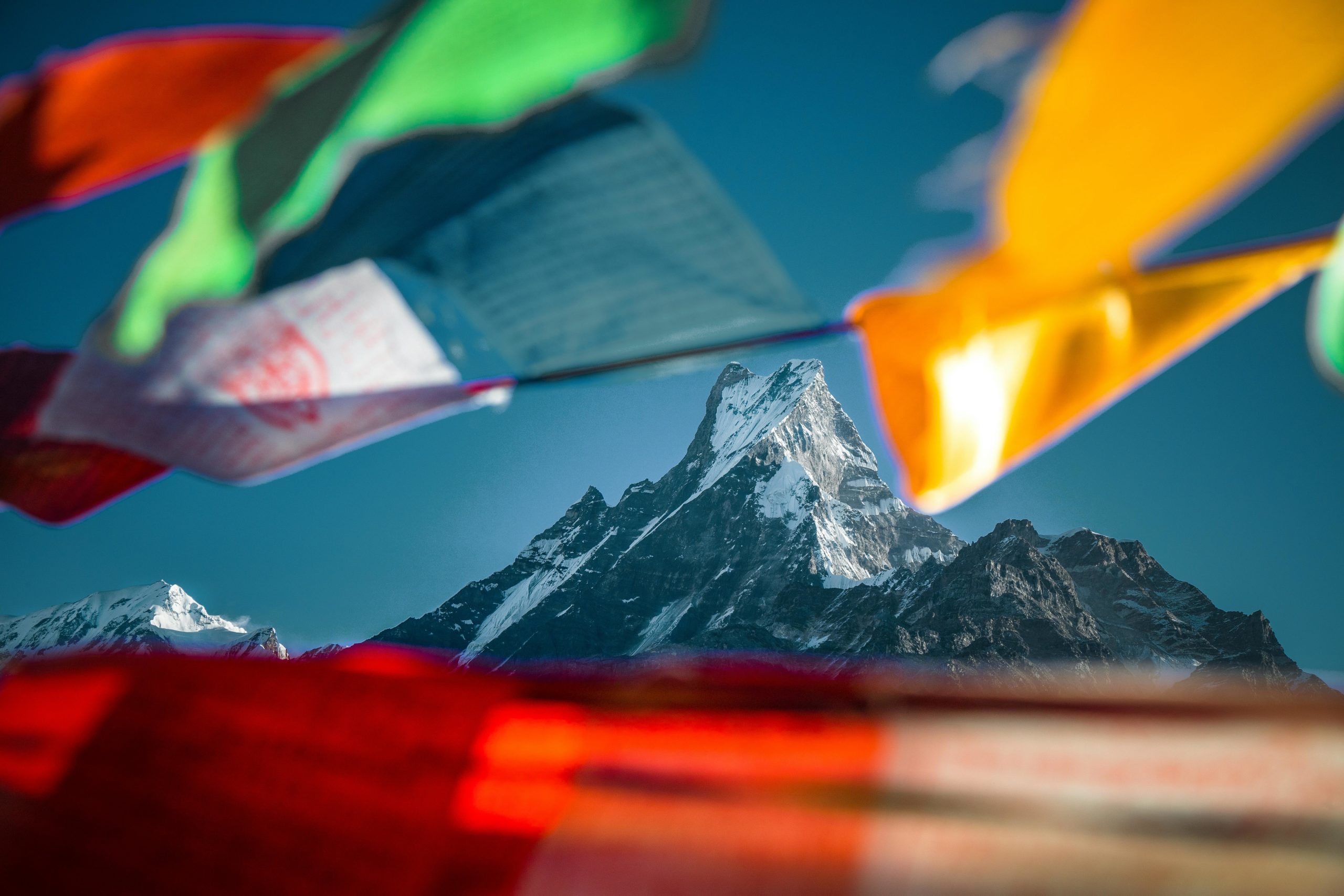 Vue du sommet de l'Everest depuis un point de vue en contrebas. Des tissus népalais flottent au premier plan donnant un côté artistique à la photo.